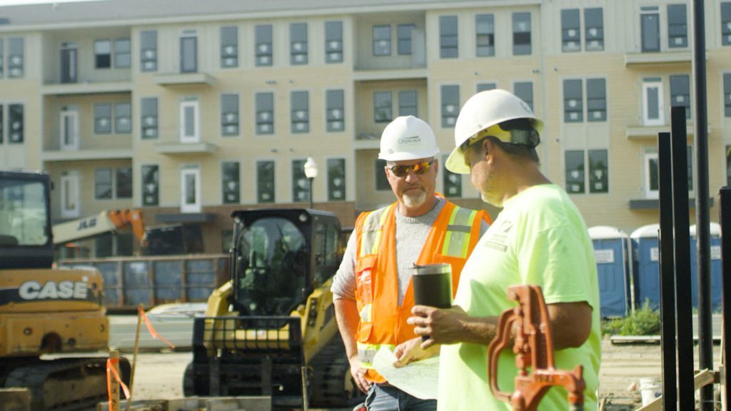 two construction men talking near buildings
